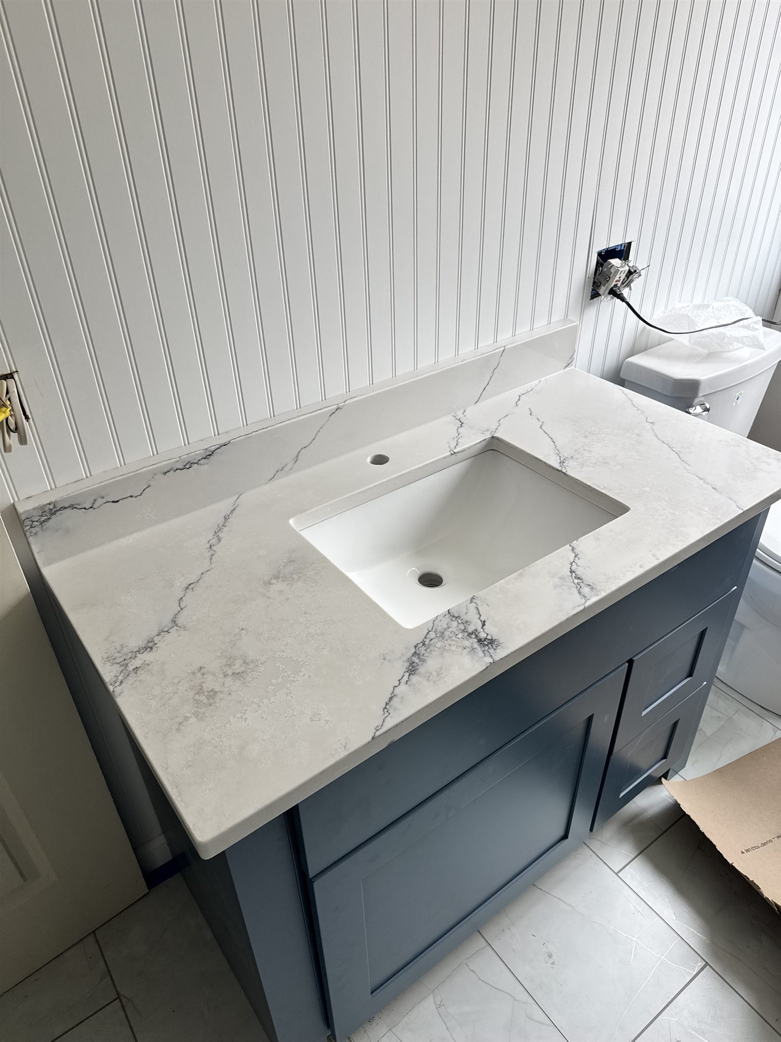 Marble-look quartz vanity top with a backsplash and undermount sink on a navy shaker vanity