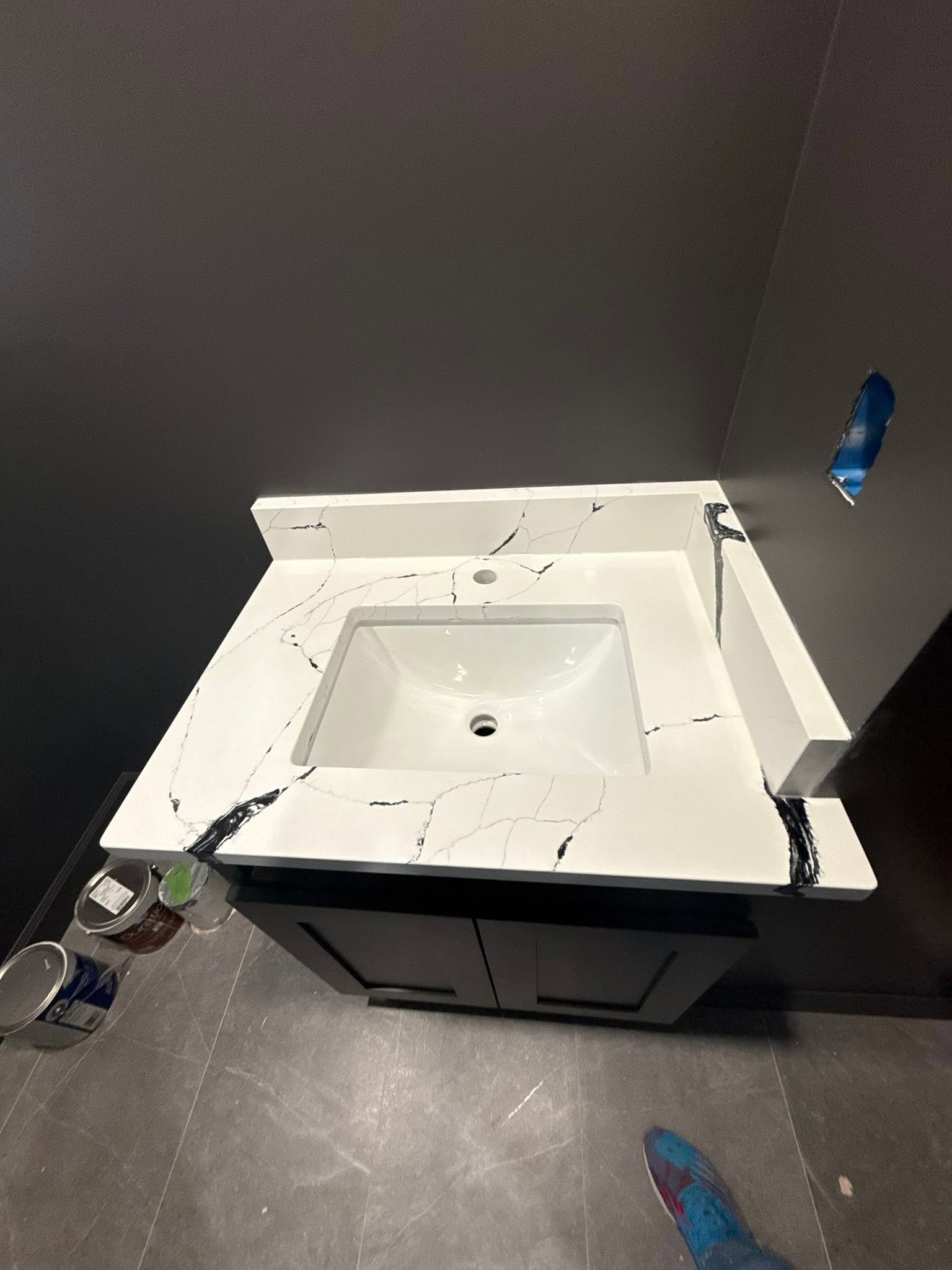 White quartz vanity top with bold black veining in a charcoal powder room